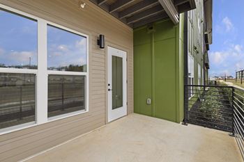 A balcony with a green door and a black railing.